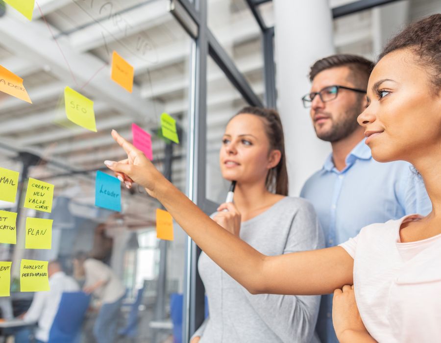 Group of researchers reviewing data from sticky notes on window