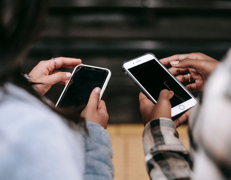 Two friends texting beside each other